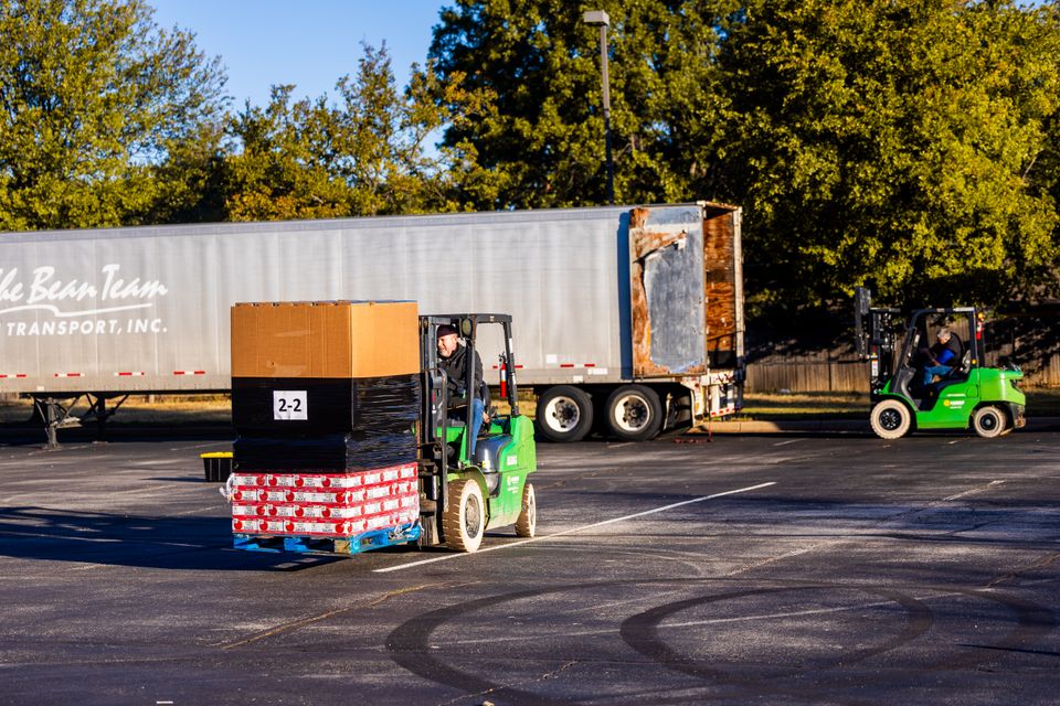 Forklift moving pallets beside a freight trailer